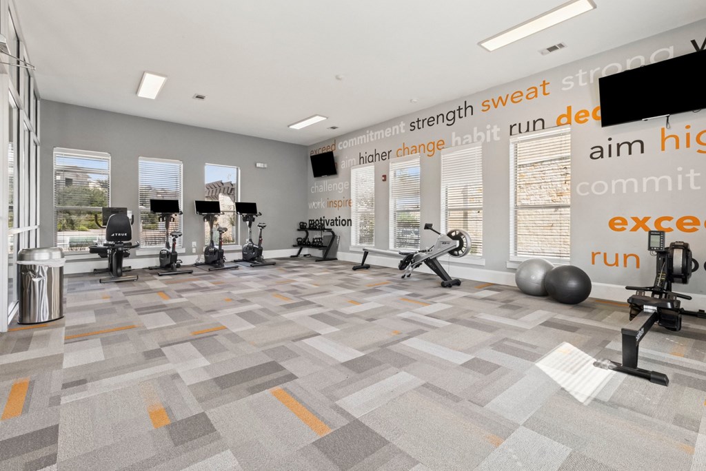 A gym with a variety of equipment and a motivational quote on the wall.