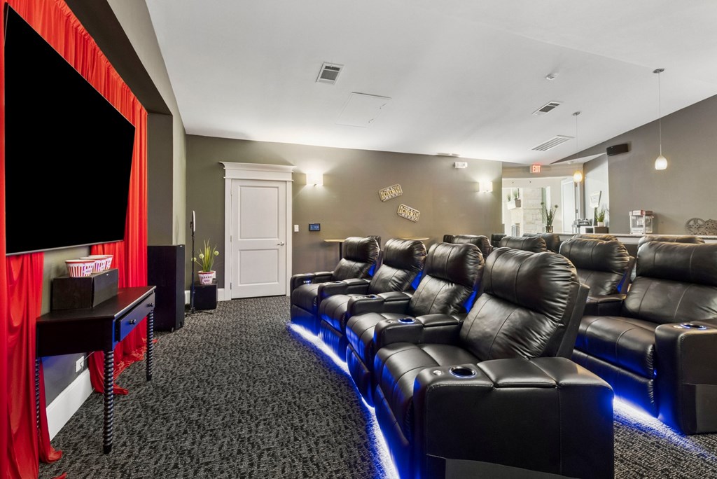 A home theater with black leather seats and a red curtain.