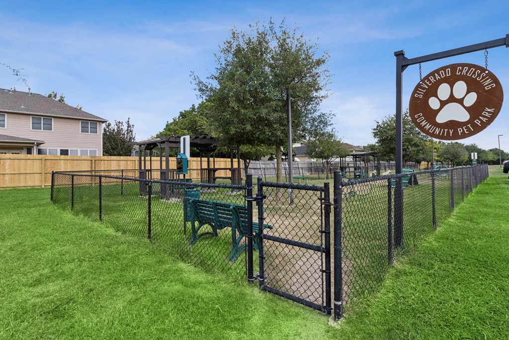 A sign for a community pet park is displayed on a fence.