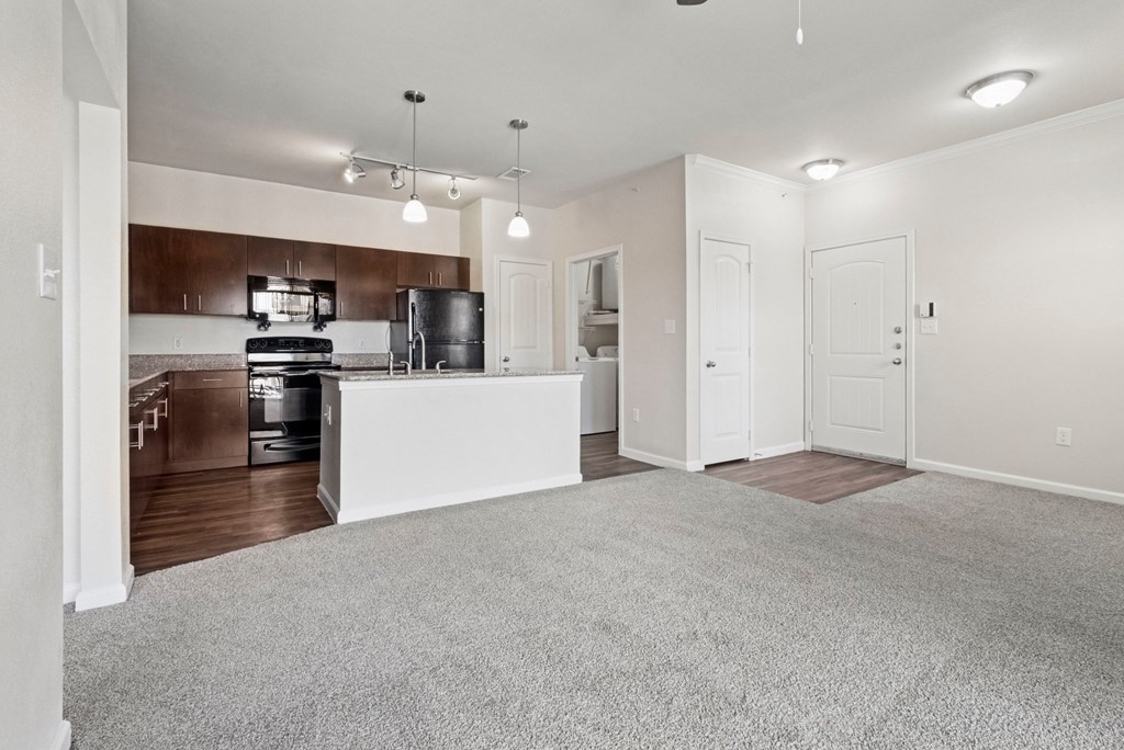 A spacious living room with a kitchen in the background.