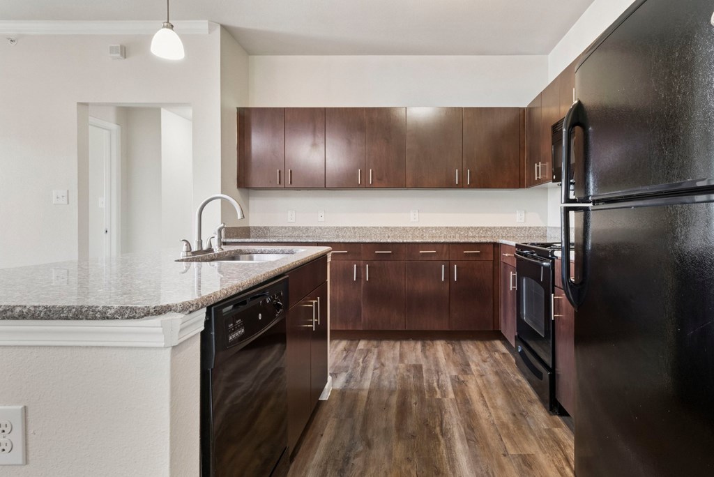 A kitchen with dark wood cabinets and black appliances.