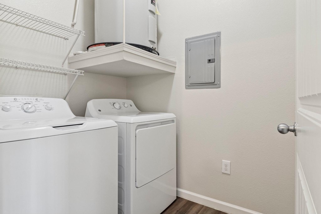 A white dryer and washer are on a shelf in a laundry room.