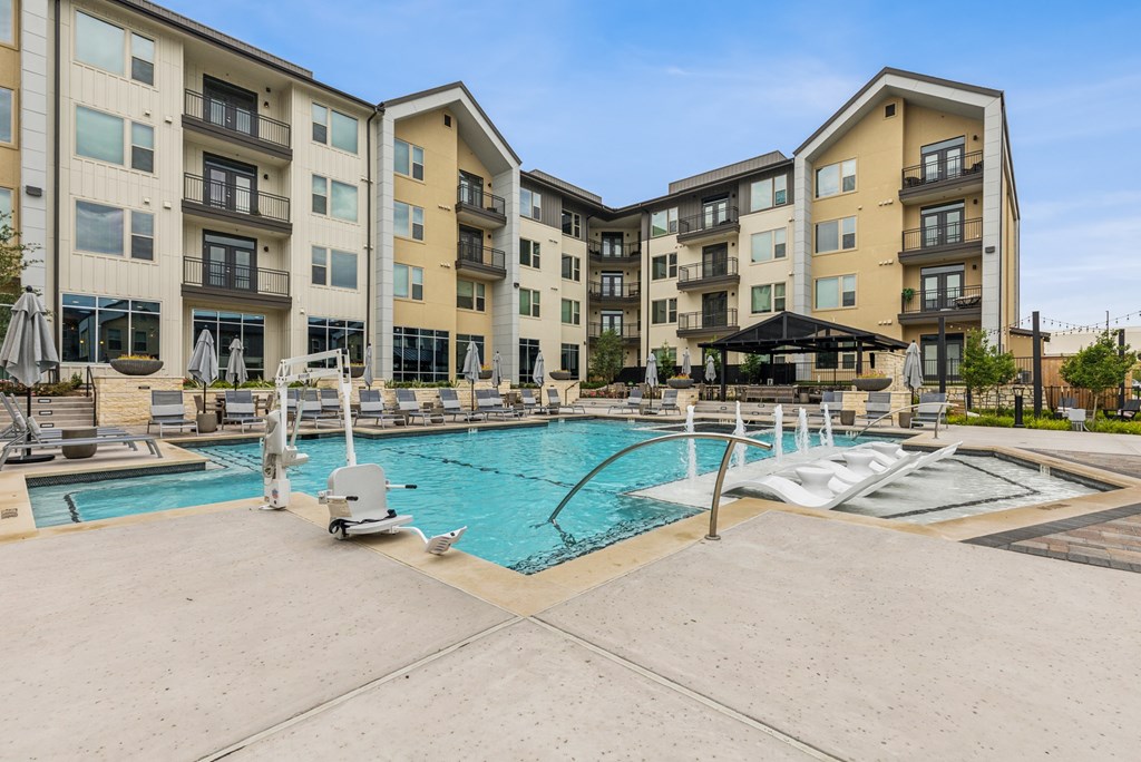 A large outdoor swimming pool with a slide in front of apartment buildings.