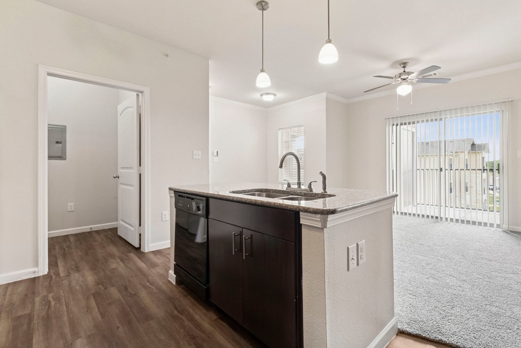 A kitchen with dark wood floors and white walls.