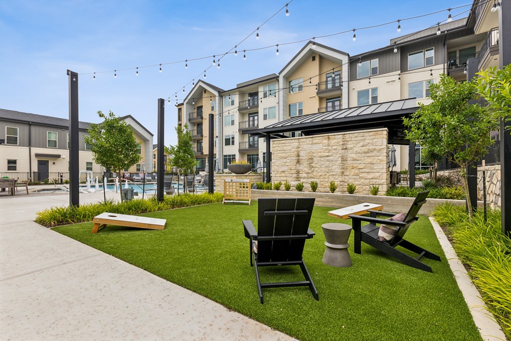 A black chair sits on a lawn in front of a building.