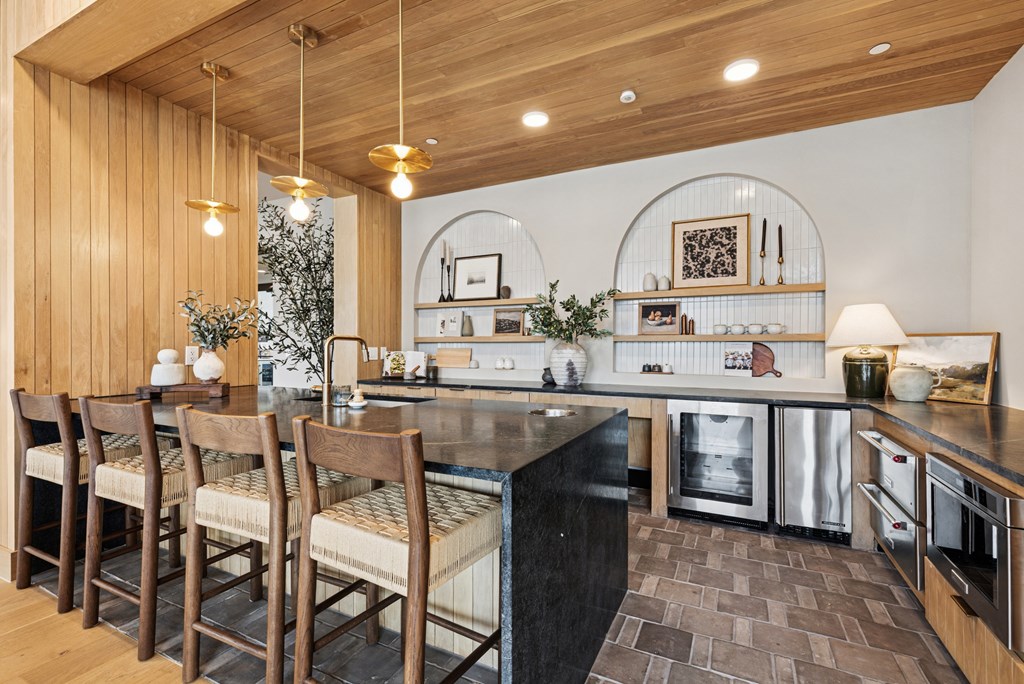 A modern kitchen with wooden chairs and a black counter.