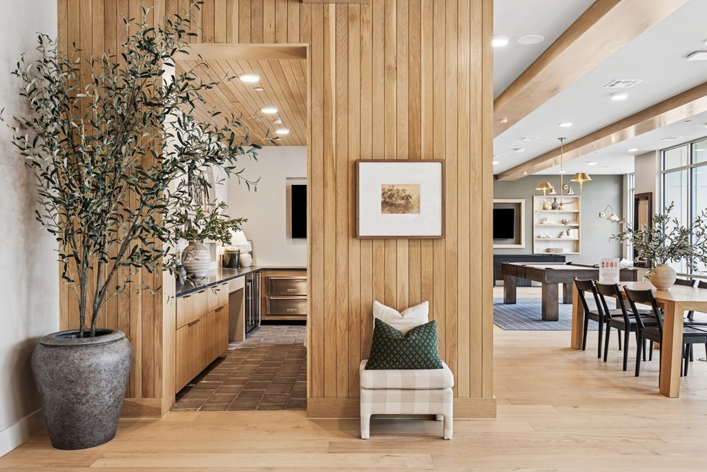 A room with a large tree in a pot and a framed picture on the wall.