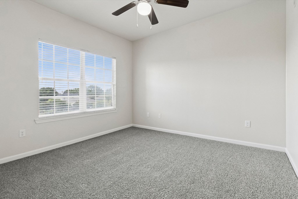 A room with a ceiling fan and a window with blinds.