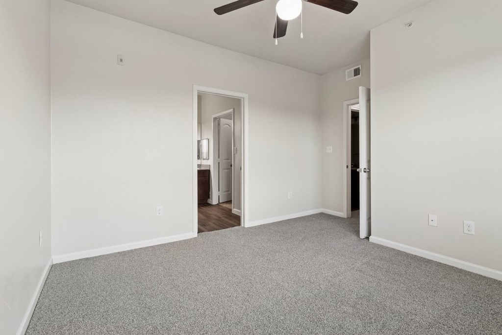 A room with a ceiling fan and carpeted floor.