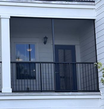 A balcony with a black railing and a window.