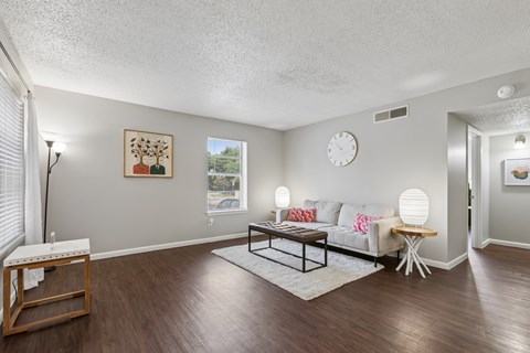A living room with a white couch, a wooden coffee table, and a painting on the wall.
