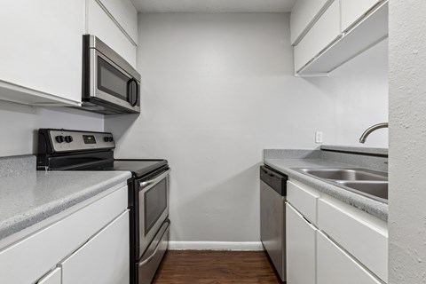A kitchen with white cabinets and a black microwave.