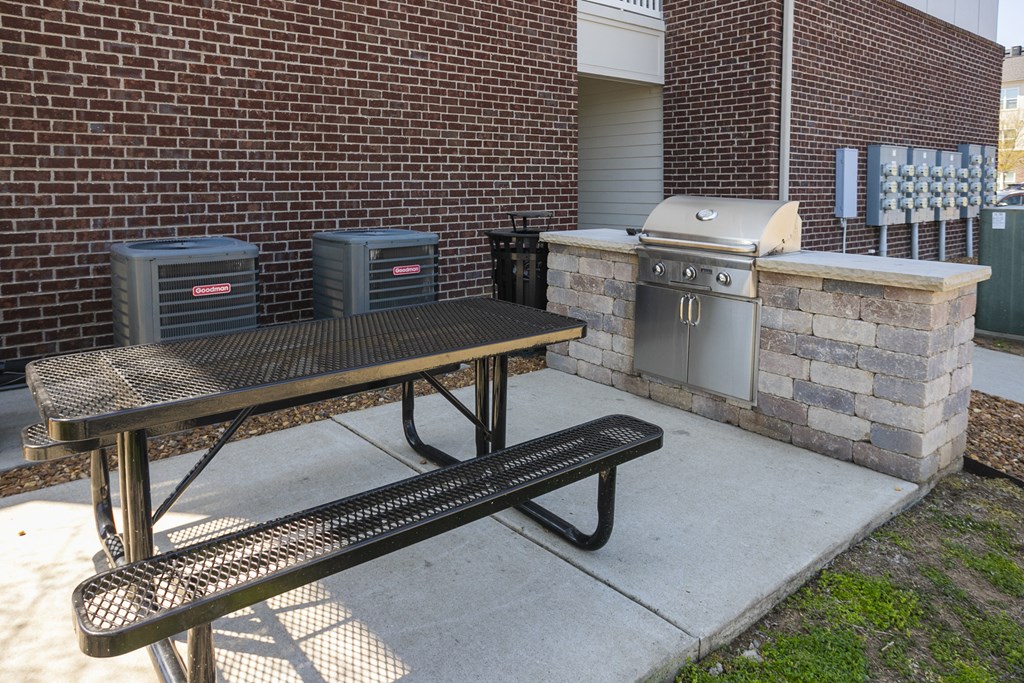 a picnic table and grill in front of a brick building