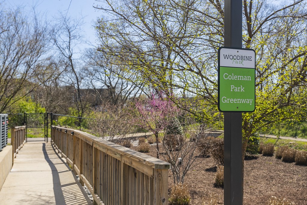 a wooden bridge in a park with a sign that reads
