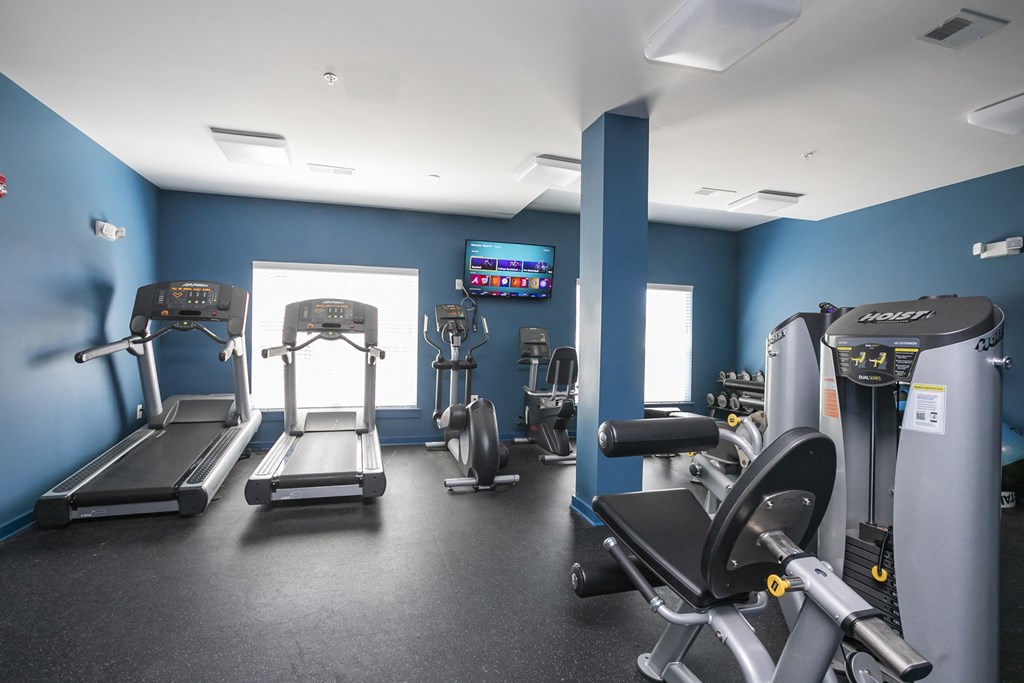 a large fitness room with cardio equipment and a flat screen tv