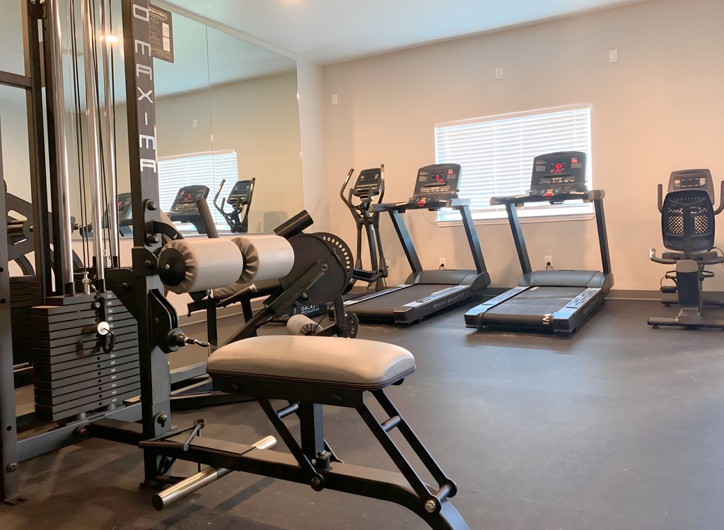 a gym with cardio equipment and mirrors in a building