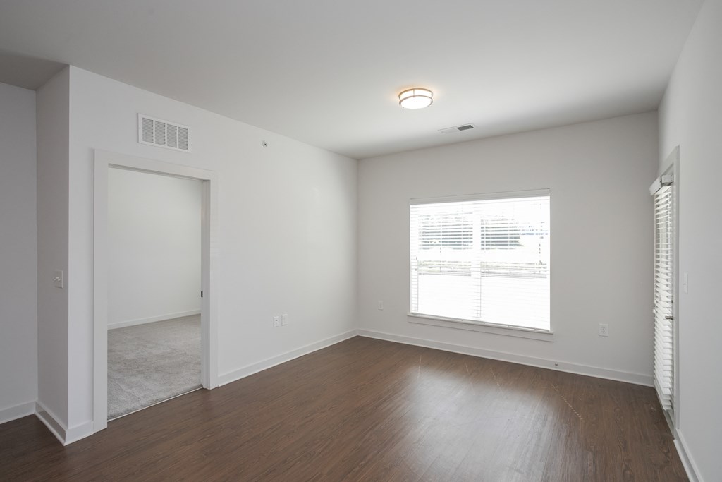 a bedroom with hardwood floors and a large window