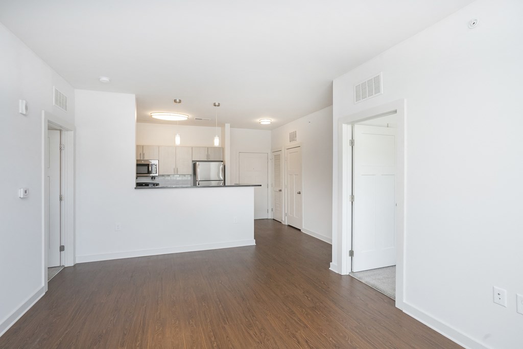 a bedroom with a medium sized bed and a kitchen in the background