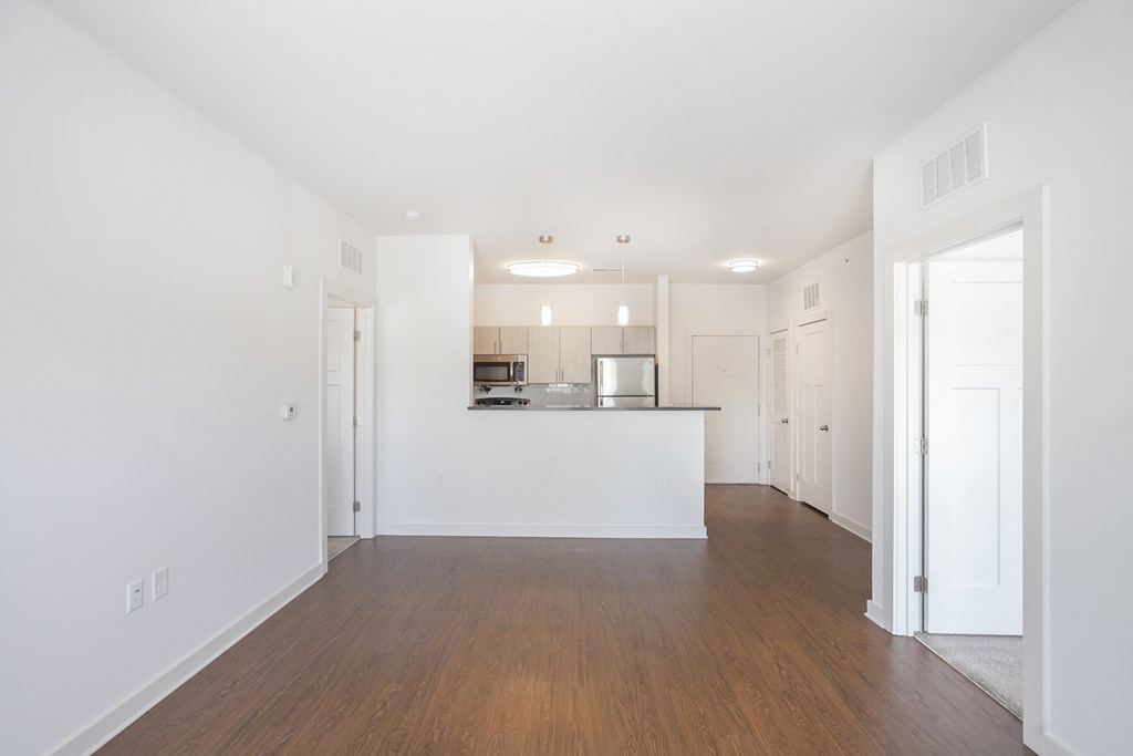 a bedroom with a medium sized bed and a kitchen in the background