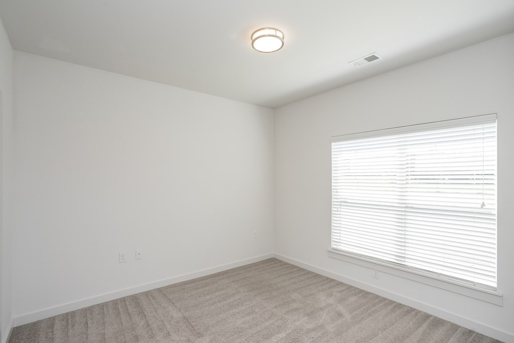 a bedroom with white walls and a large window