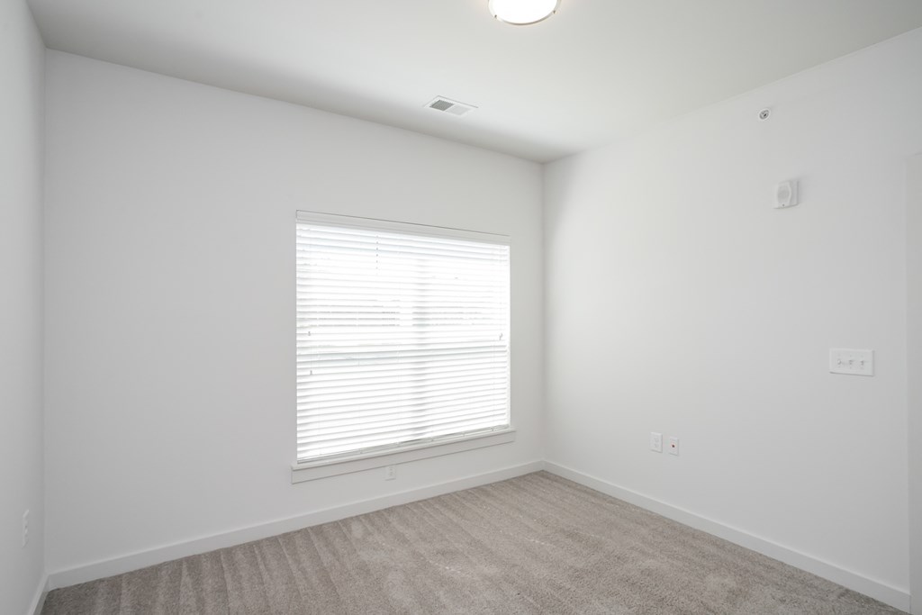 a bedroom with white walls and a window