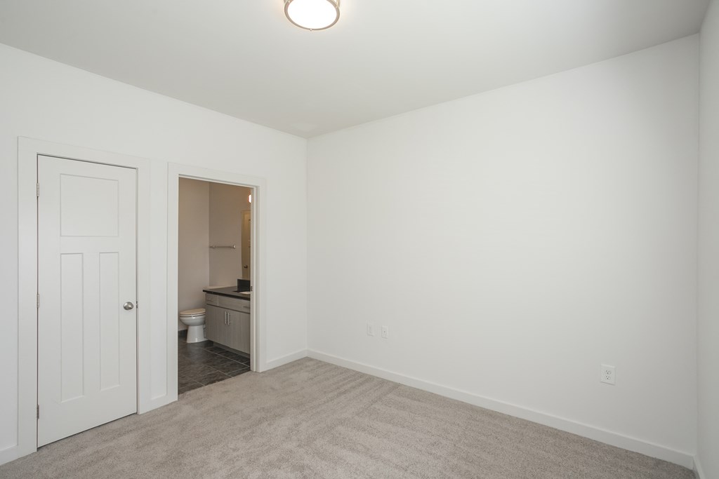a bedroom with white walls and a beige carpet