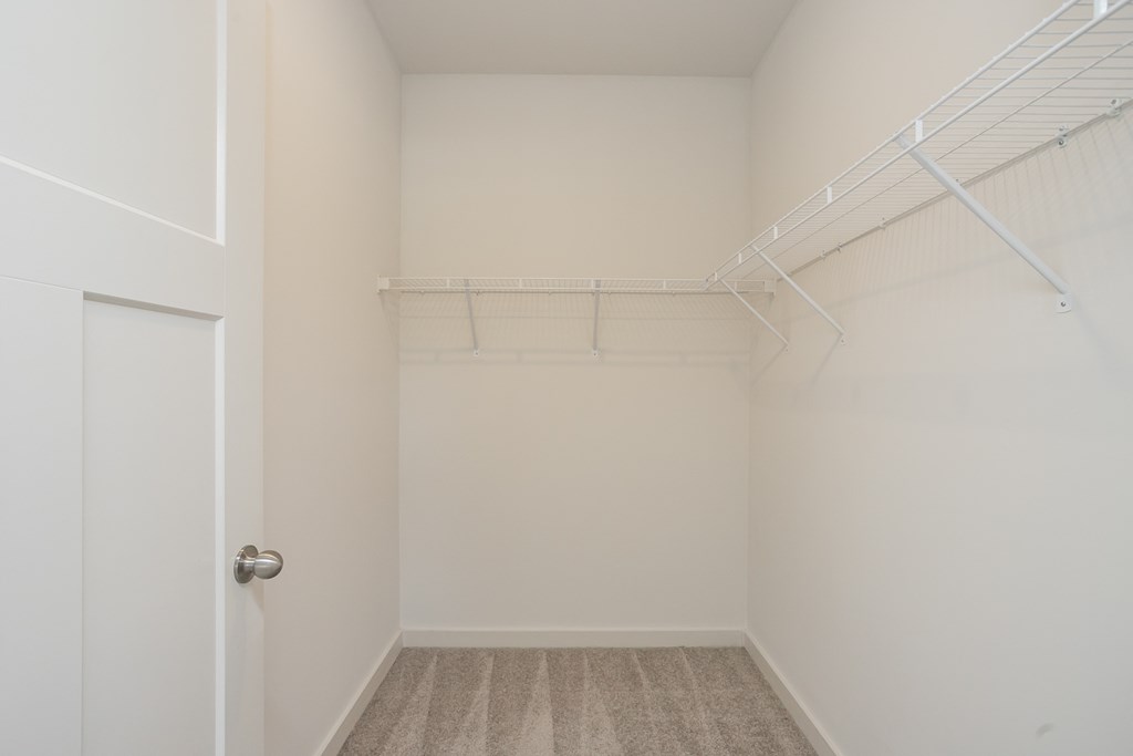 an empty closet in a home with white walls and a door