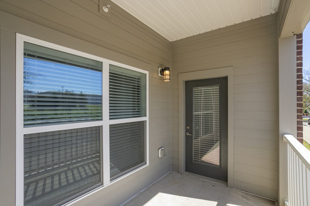 the front porch of a home with a black door and large windows