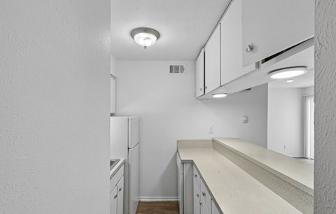A kitchen with white cabinets and a white fridge.