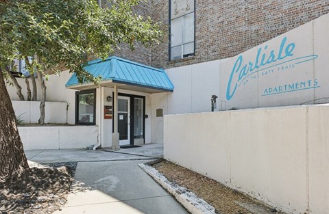 The entrance to Carlisle Apartments is shown with a blue awning.