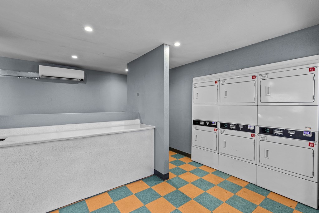 a washer and dryer room with grey walls and a yellow and blue tile floor