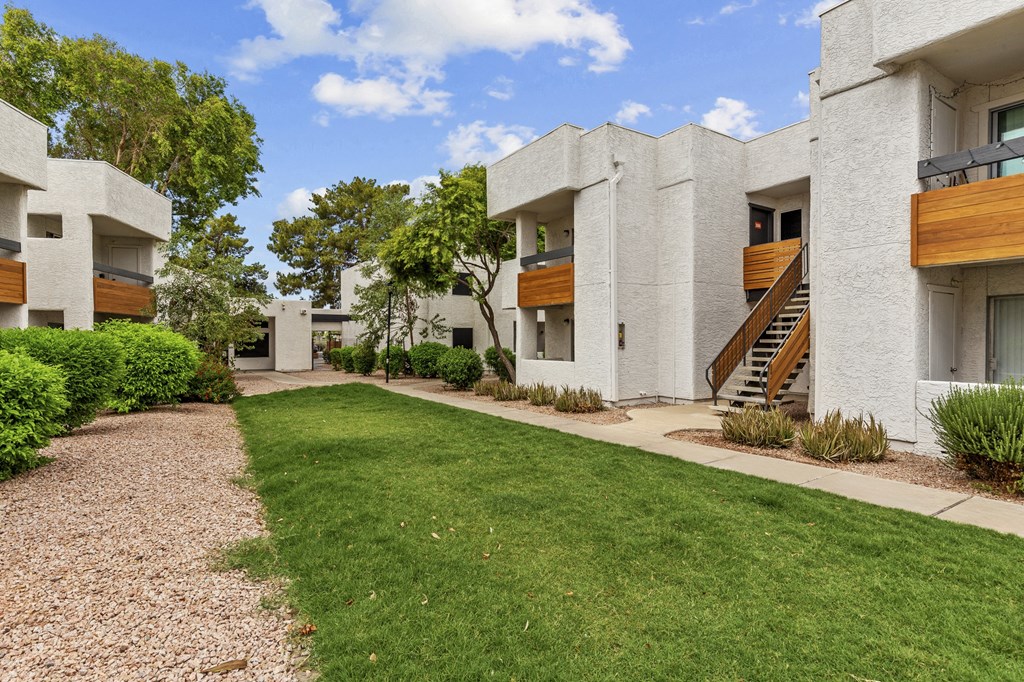a grassy area with trees in the background at the whispering winds apartments in pearland,