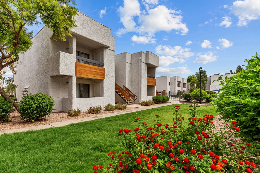 a building with a green lawn and red flowers in front of it