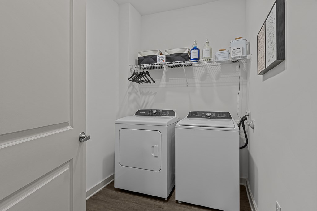 A laundry room with two washing machines and a shelf above them.