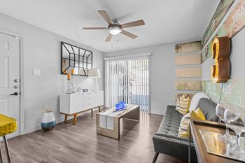 A living room with a white sofa, a yellow chair, and a wooden coffee table.