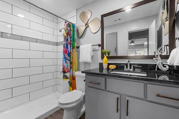 A bathroom with a white tiled shower area and a white toilet.