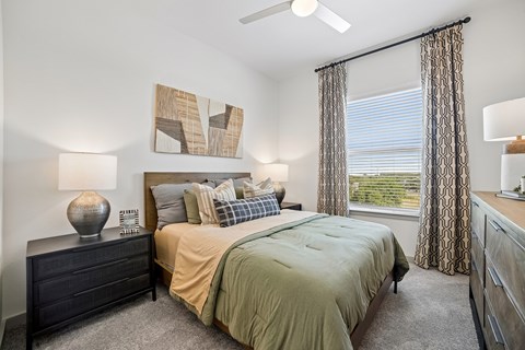 A bedroom with a bed, dresser, and window.