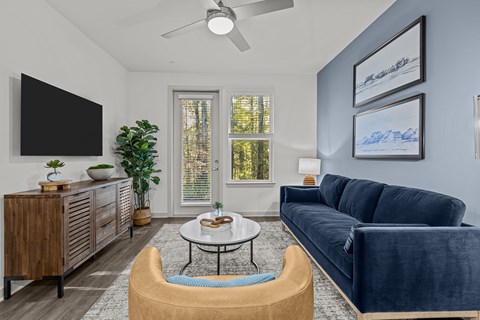 A living room with a blue couch and a television on the wall.