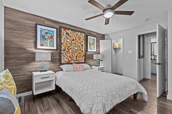 A bedroom with a bed, nightstand, and a painting on the wall.