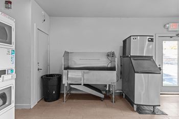 A clean, empty kitchen with a trash can and a sink.