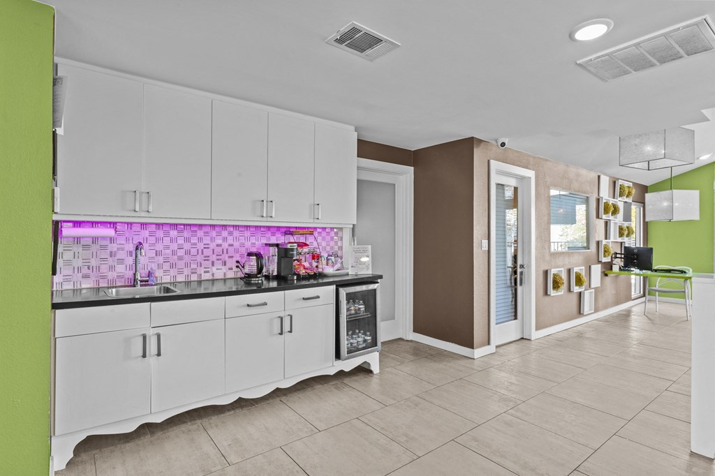 a kitchen with white cabinets and a purple and white tile wall