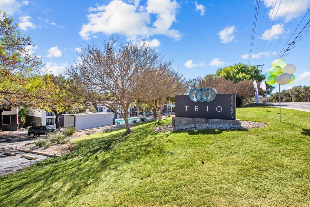 a sign that says in front of a lawn with trees