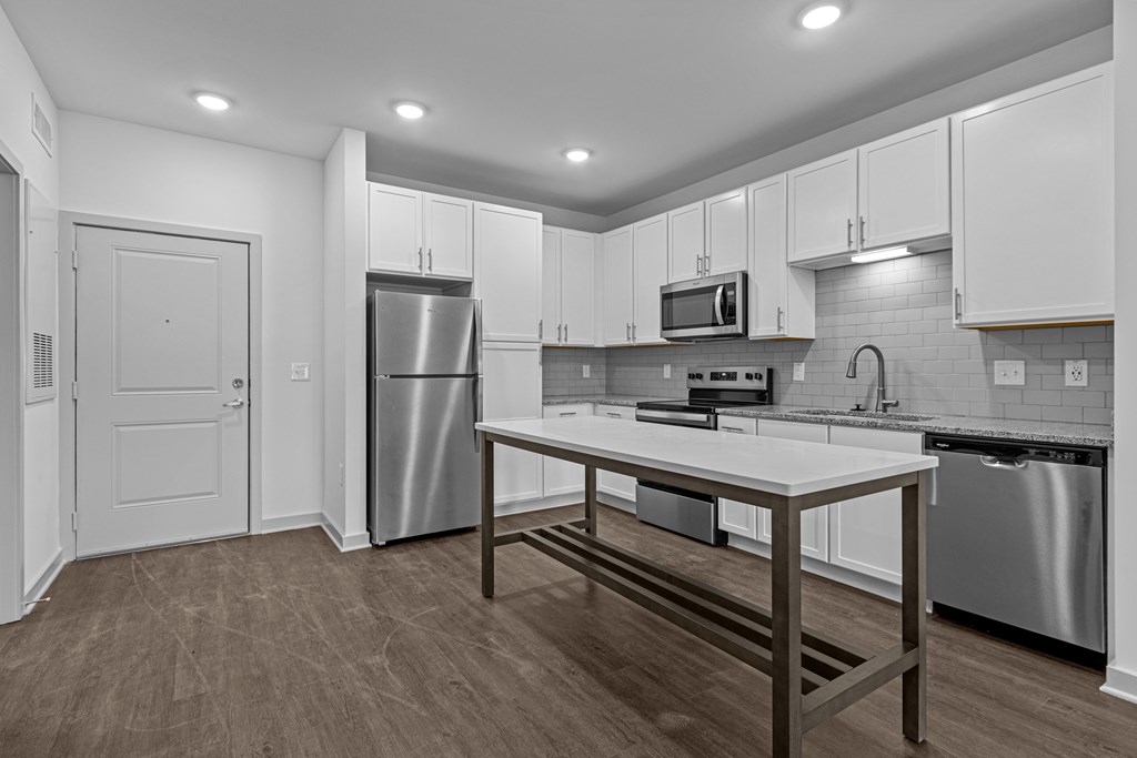 A kitchen with a stainless steel refrigerator, microwave, and wooden table.