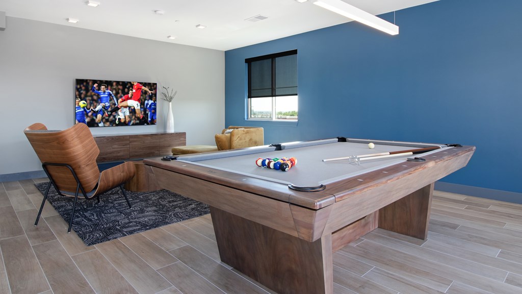 A pool table with a chair and a painting in the background.