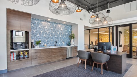 A modern office space with a wooden desk and chairs, a TV, and a patterned backsplash.
