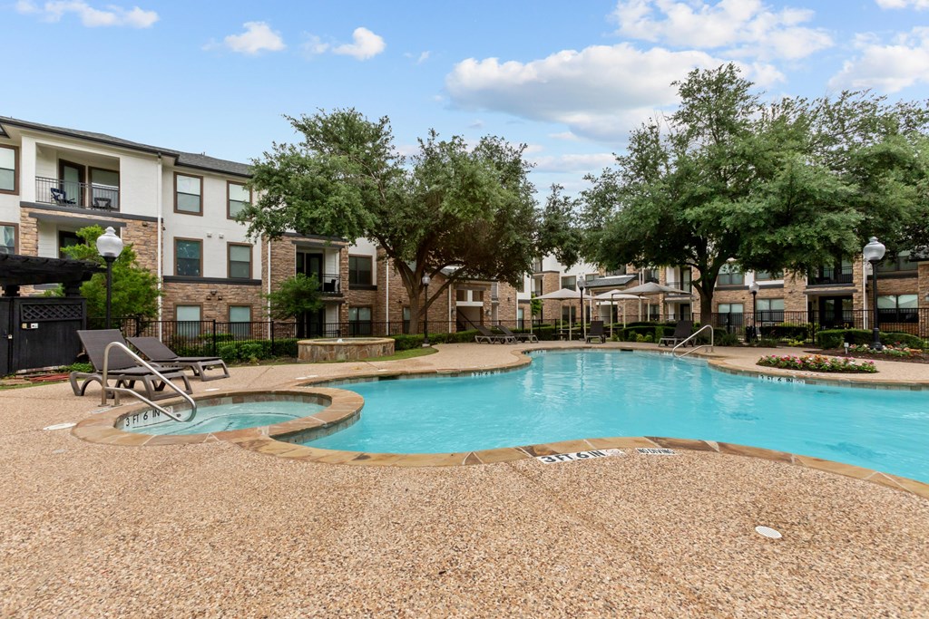 A swimming pool surrounded by a gravel area and trees.