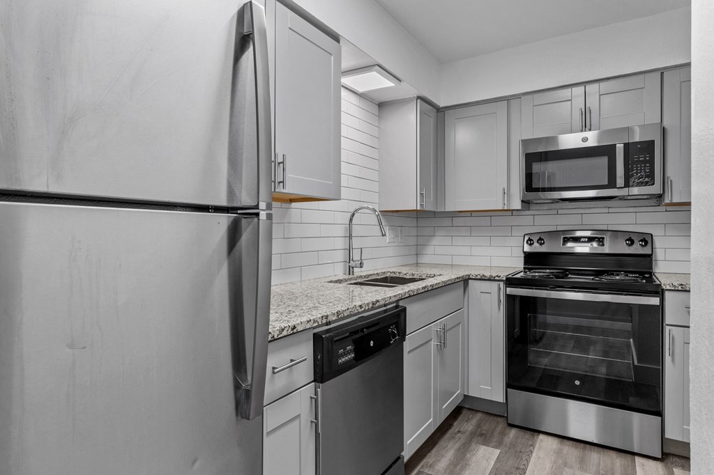 an all white kitchen with stainless steel appliances and white cabinets