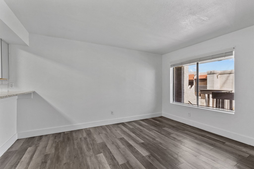 the living room of an apartment with wood flooring and a large window