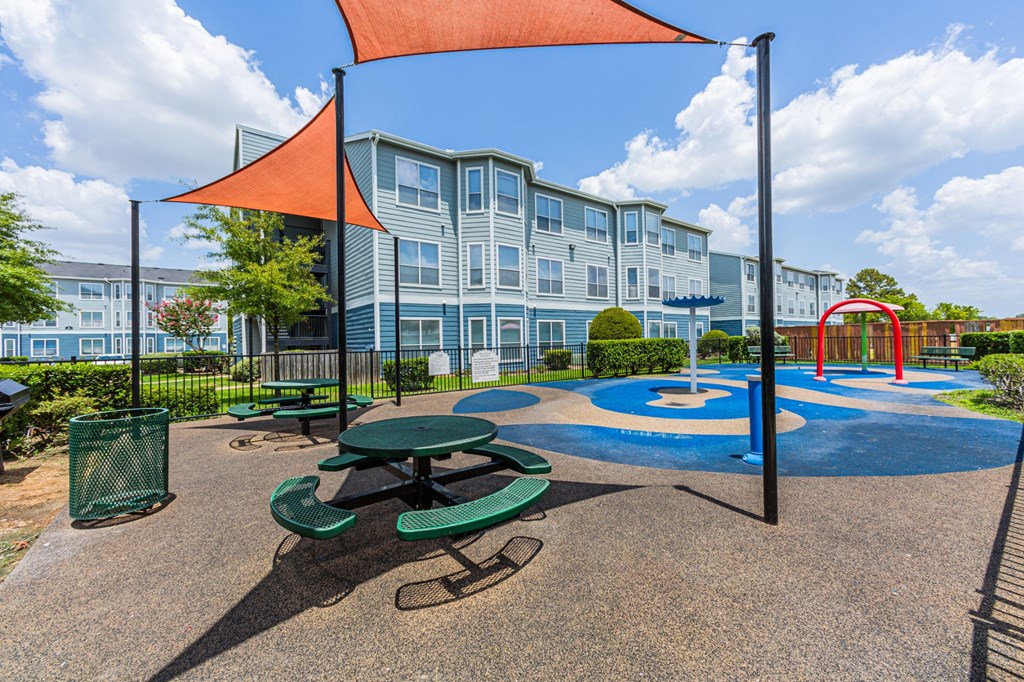 a playground with a picnic table in front of an apartment building