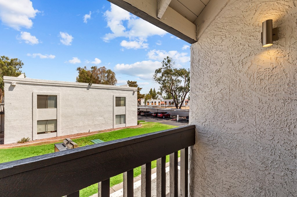 the view from the balcony of a condo with a yard and a building